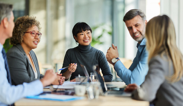 five attorneys sitting at a table smiling and talking